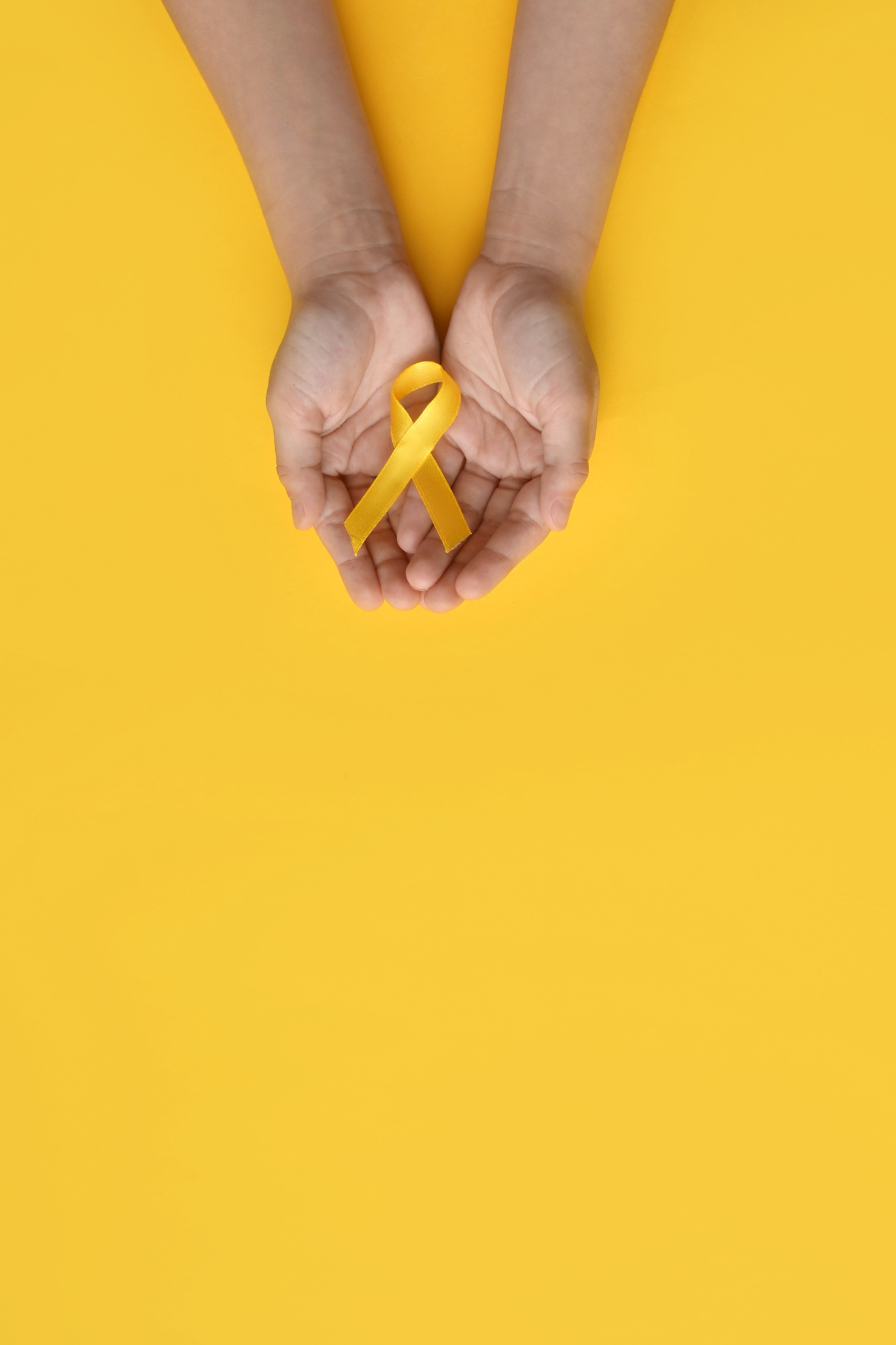 International Childhood Cancer Day. Child hands holding yellow gold ribbon. Sarcoma Awareness, Bone cancer, childhood cancer awareness. Concept I Am and I Will. banner. copy space